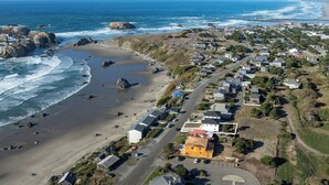 Vista aérea de un pueblo costero con playa, casas y una carretera.