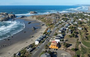 Una vista aerea di una cittadina costiera con spiaggia, case e una strada.