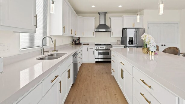 Una cocina moderna con armarios blancos, electrodomésticos de acero inoxidable y piso de madera.