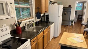 A kitchen with wooden cabinets, a microwave, a sink, and a refrigerator. - Waterfront oasis perfect for couples or fishermen. (Scottsboro)