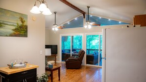 A spacious living area with a wooden floor, a dining table, a sofa, and a ceiling fan. - Waterfront oasis perfect for couples or fishermen. (Scottsboro)