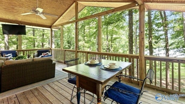 A covered outdoor deck with a table set for dining, chairs, and a sofa. - Waterfront oasis perfect for couples or fishermen. (Scottsboro)