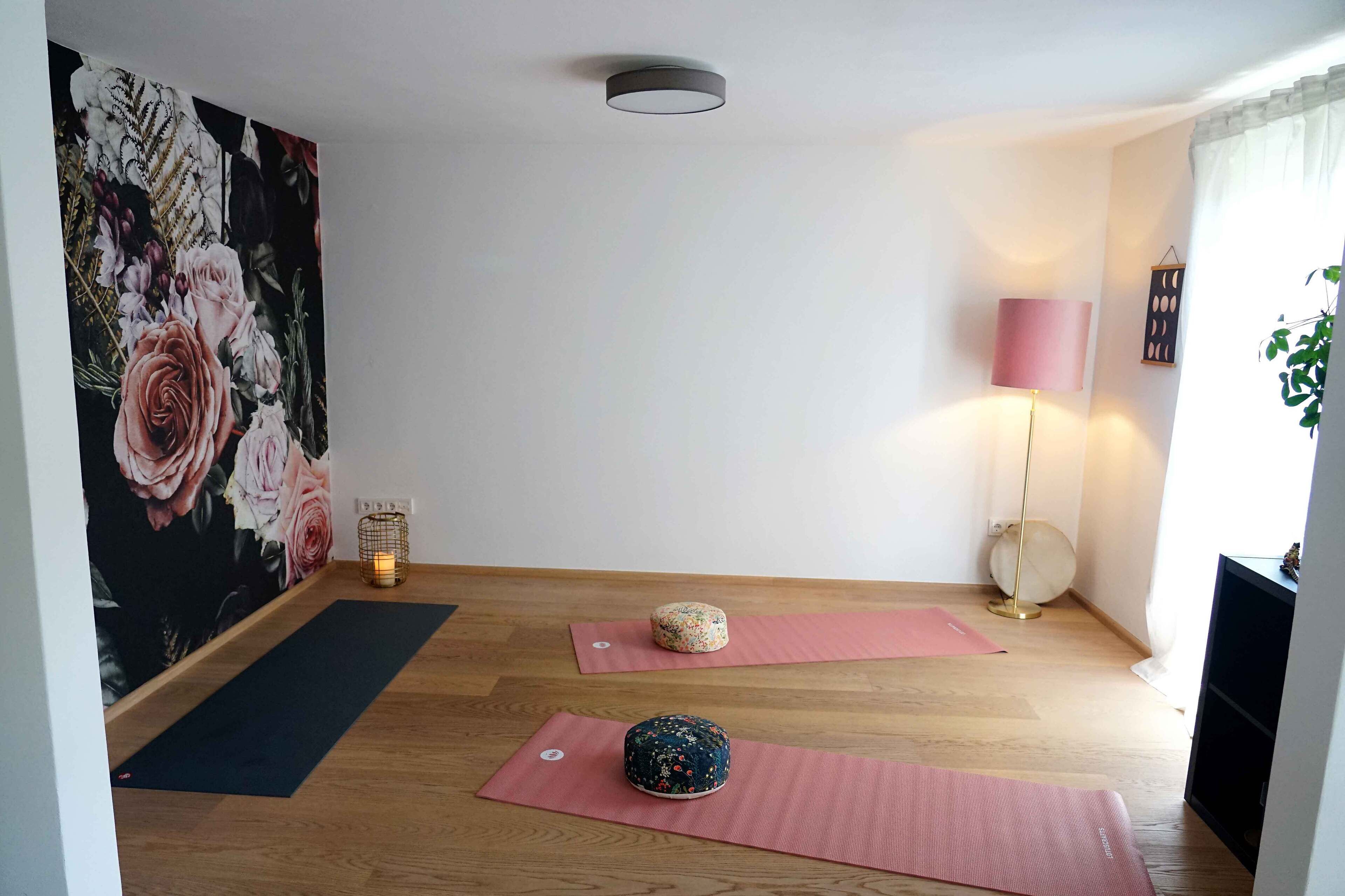 A yoga room with wooden flooring, pink mats, and a floral wall mural.