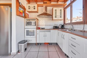 A kitchen with white cabinets, a stainless steel range hood, a microwave, a toaster, and a sink.