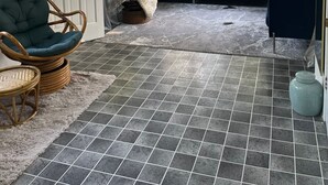 A room with a blue sofa set, a wicker chair, a rug, and a tiled floor. - Lake Huron Getaway: Cozy Cottage, Private Access, Second-Row Location (Dashwood)