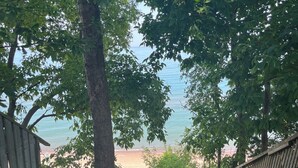 A staircase leading to a beach with a chain-link fence on one side and trees on the other. - Lake Huron Getaway: Cozy Cottage, Private Access, Second-Row Location (Dashwood)