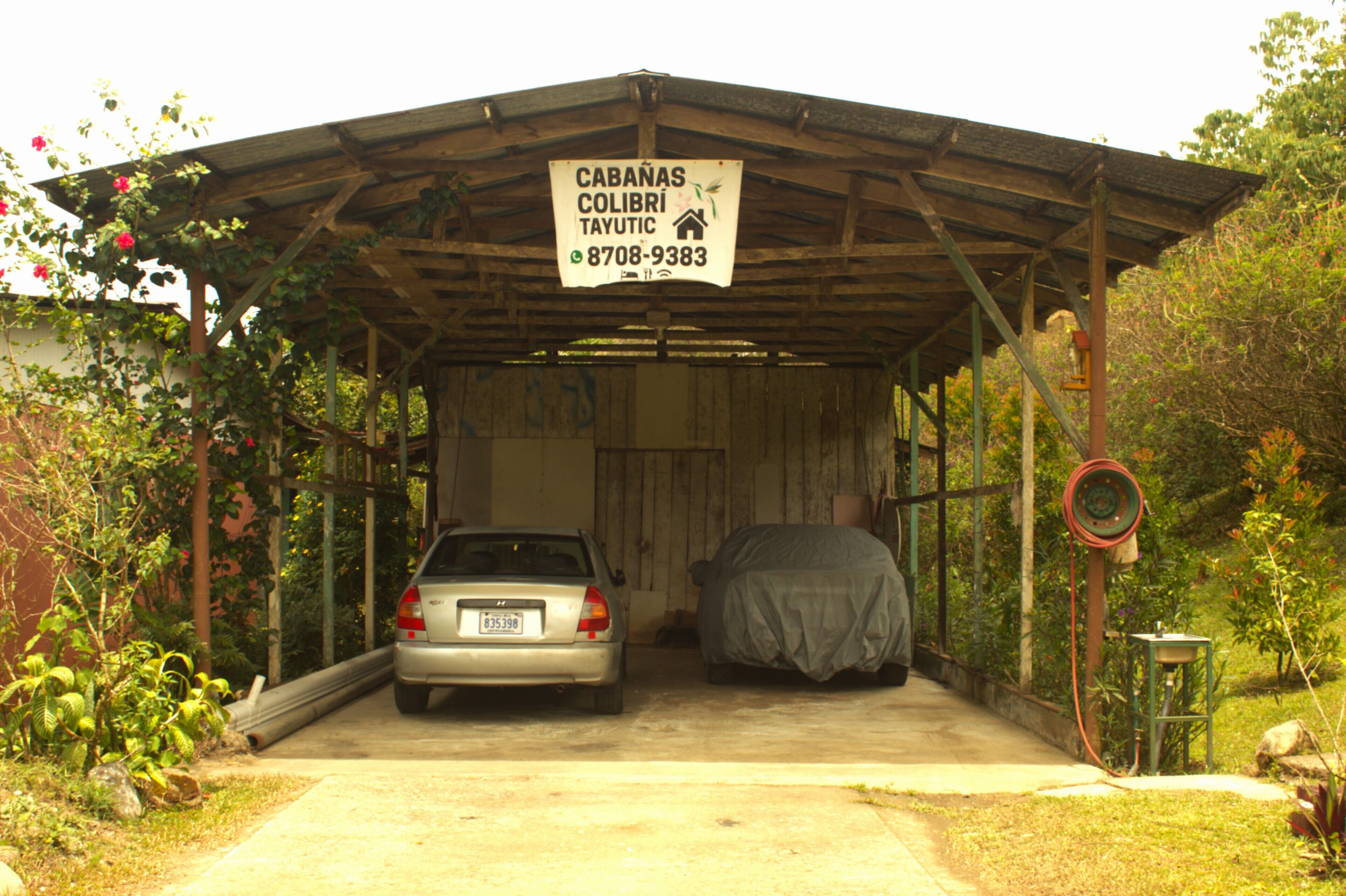 Un centre de lavage automobile abrité, avec une enseigne indiquant les services proposés et un numéro de téléphone à contacter.