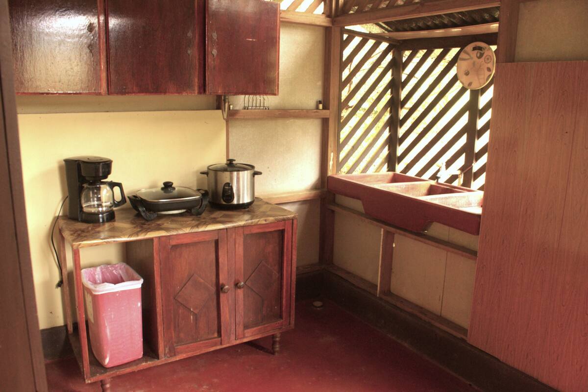 A compact kitchen with wooden cabinets, a coffee maker, a pot, and a sink.