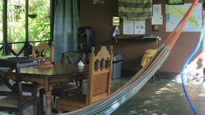 A rustic room with a wooden dining table, chairs, a hammock, a TV, and a map on the wall. - Cabañas Colibrí Tayutic (Tayutic)