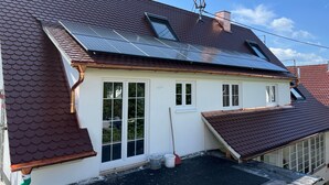 Een huis met een schuin dak, zonnepanelen en een raam met uitzicht op de straat.