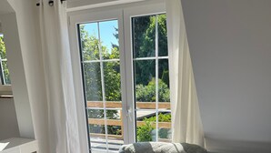 Een woonkamer met een bank, een salontafel en een schuifdeur die leidt naar een balkon.