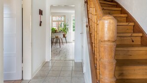 Una escalera de madera que conduce a una habitación con piso de baldosas y una puerta a la izquierda.