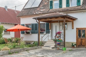 Une maison avec un porche, des meubles d’extérieur et des plantes en pot.