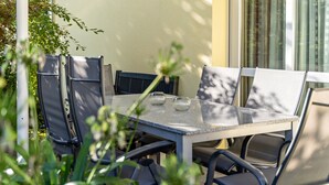 A table with chairs, a glass vase, and a plant in the foreground. - Apartment 'Im Rosengarten' with Mountain View, Private Terrace and Wi-Fi (Zell am Harmersbach)