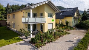 A two-story house with a balcony, solar panels, and a well-maintained garden. - Apartment 'Im Rosengarten' with Mountain View, Private Terrace and Wi-Fi (Zell am Harmersbach)