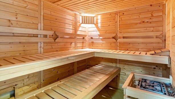 A sauna with wooden benches and a stone bench, wooden walls, and a sloped ceiling. - Apartment 'Im Rosengarten' with Mountain View, Private Terrace and Wi-Fi (Zell am Harmersbach)