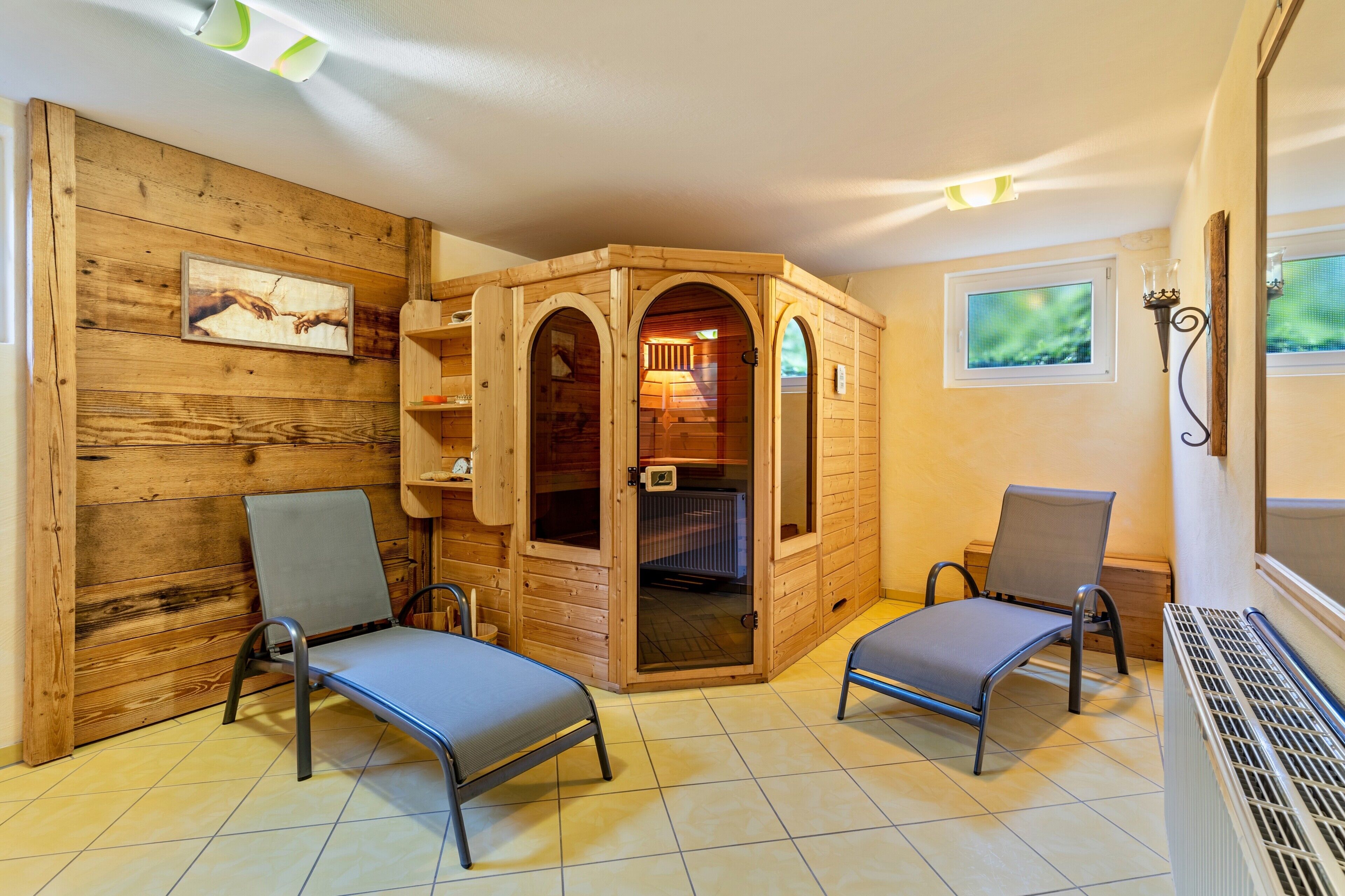 Uma sala de sauna de madeira com duas cadeiras, um banco e uma parede de madeira com uma imagem.