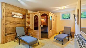 Uma sala de sauna de madeira com duas cadeiras, um banco e uma parede de madeira com uma imagem.