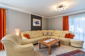 Un salon avec un canapé d’angle, une table basse en bois et un lampadaire.
