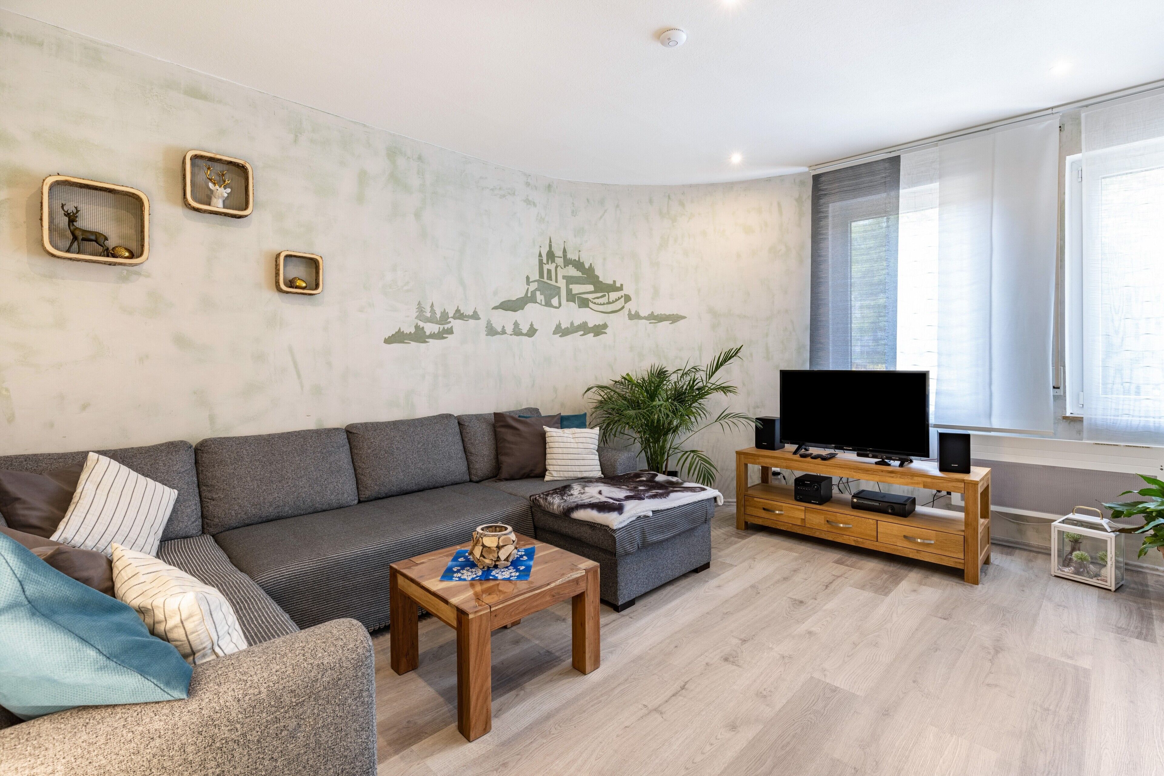 Een woonkamer met een bank, salontafel, tv-meubel en decoratieve wanddecoratie.