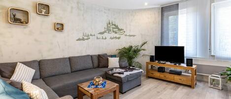 Een woonkamer met een bank, salontafel, tv-meubel en decoratieve wanddecoratie.