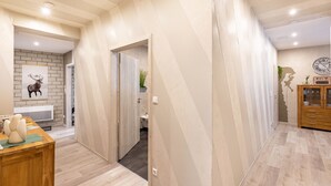 A modern interior with a wooden floor, a brick wall, a wooden cabinet, and a clock on the wall. - Premium Apartment 'Für Traufgängerle' with Private Terrace, Garden & Infrared Cabin (Albstadt)