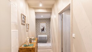 A narrow hallway with a wooden desk, a white door, and a brick wall with a mounted picture. - Premium Apartment 'Für Traufgängerle' with Private Terrace, Garden & Infrared Cabin (Albstadt)