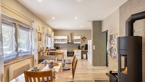 A modern kitchen with a dining area, featuring a wooden table, chairs, and a black stove. - Premium Apartment 'Für Traufgängerle' with Private Terrace, Garden & Infrared Cabin (Albstadt)