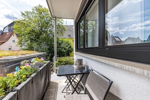 Ein Balkon mit Tisch, Stuhl und Topfpflanzen.