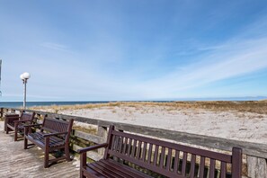 En træpromenade med bænke, der giver udsigt over stranden.