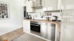 Una cocina moderna con electrodomésticos de acero inoxidable, encimera de madera y un colgador para ollas.