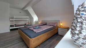 Et soveværelse med køjeseng, enkeltseng, natbord med lampe og et vindue med gardiner.