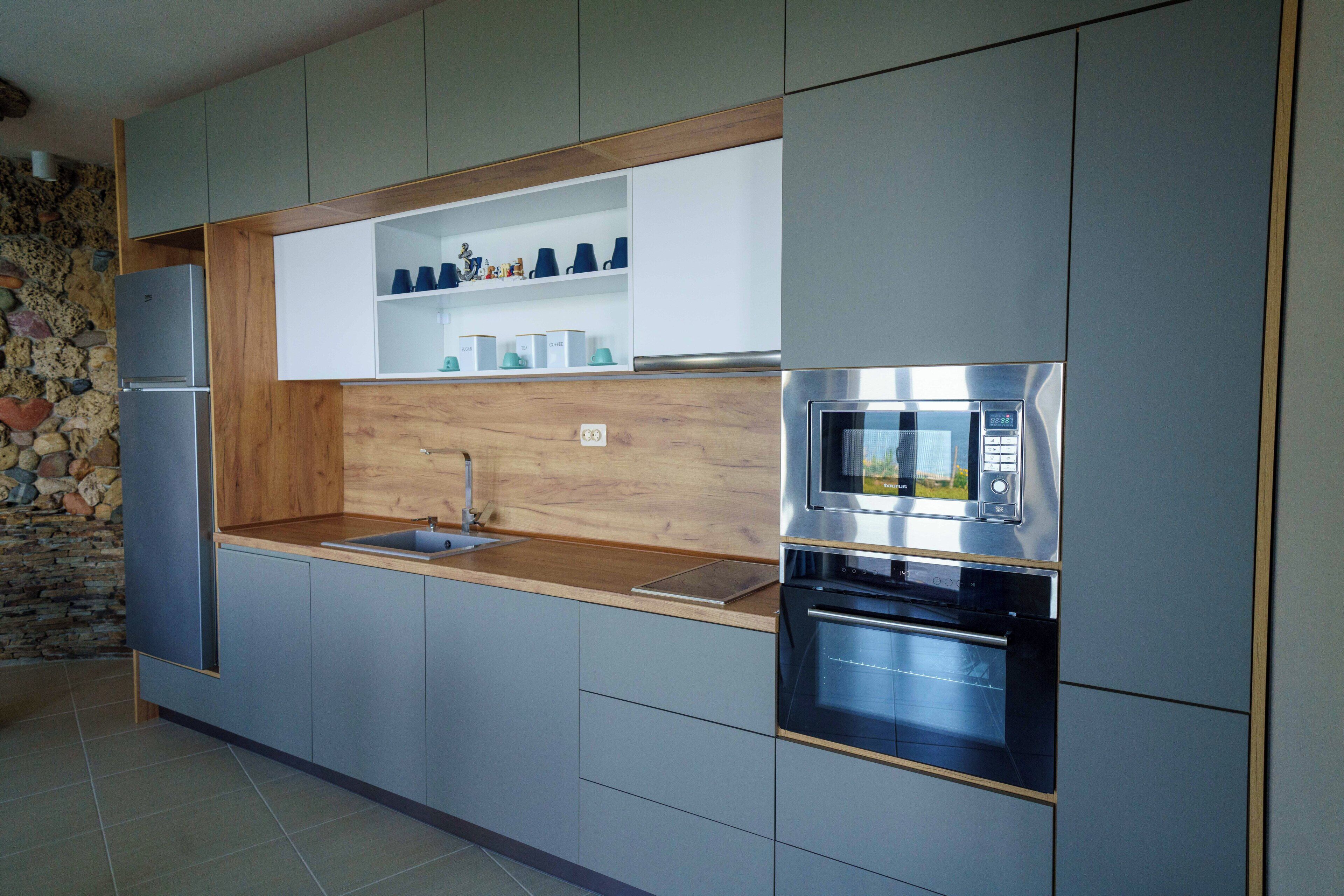 Una cocina moderna con electrodomésticos integrados, encimera de madera y pared de piedra.
