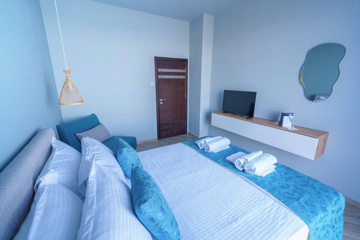 Une chambre d’hôtel moderne avec un grand lit, une télévision et un miroir dans la salle de bain.