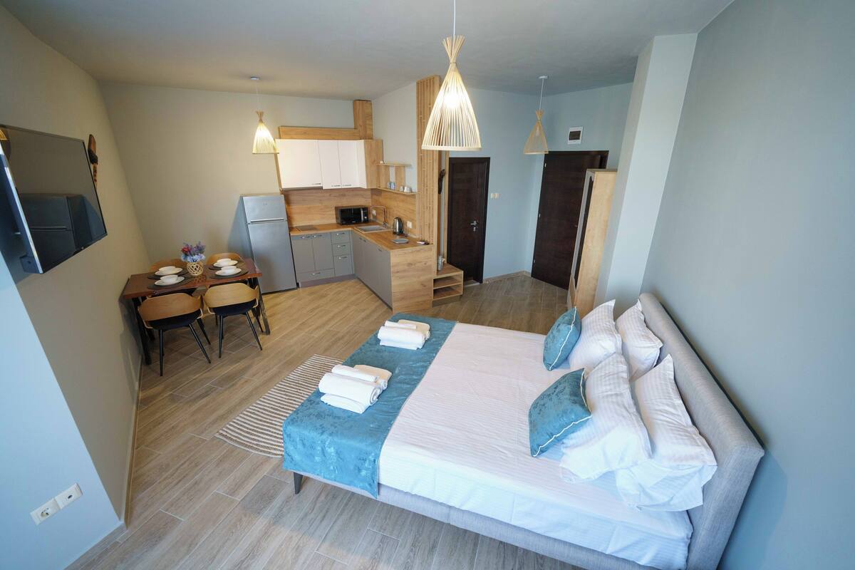 Une chambre d’hôtel moderne équipée d’un lit, d’un bureau, d’une kitchenette et d’une salle de bain.