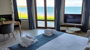 Una habitación de hotel con cama, televisión, escritorio y vistas al mar.