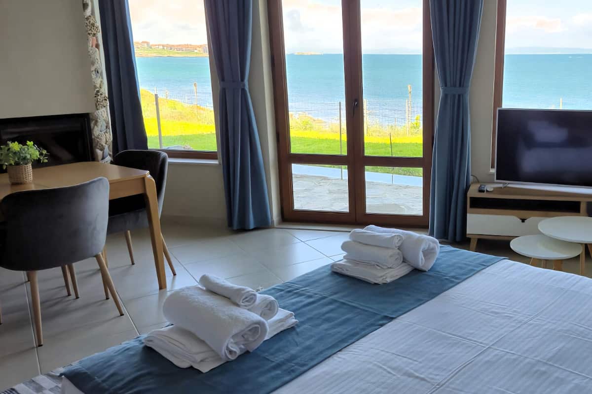 Une chambre d’hôtel avec un lit, une télévision, un bureau et une vue sur la mer.