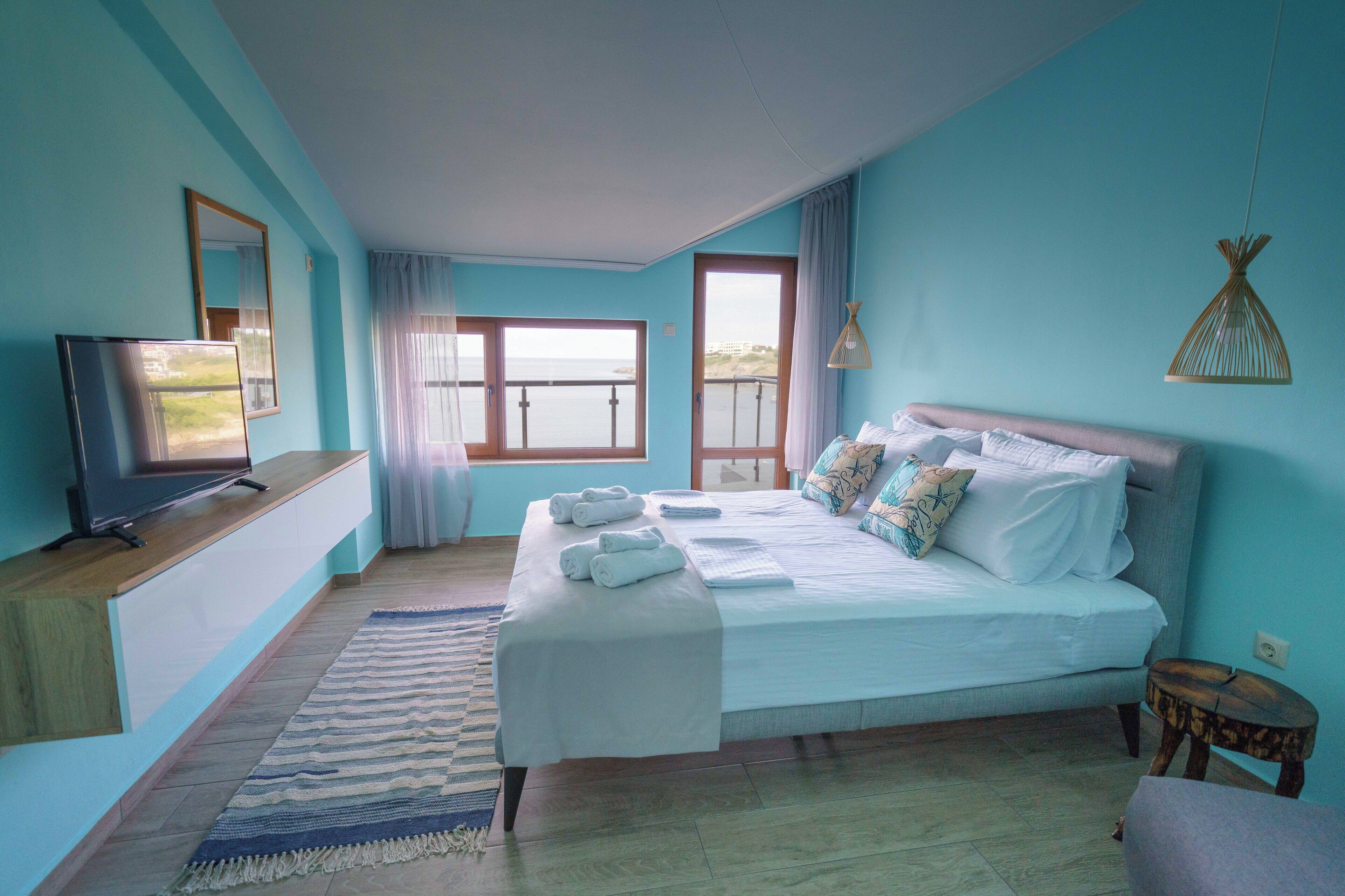 A bedroom with a bed, a television, a window with a view, and a small table.