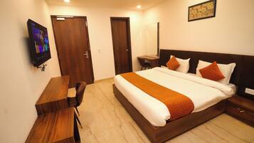 A hotel room with a bed, a desk, and a television.