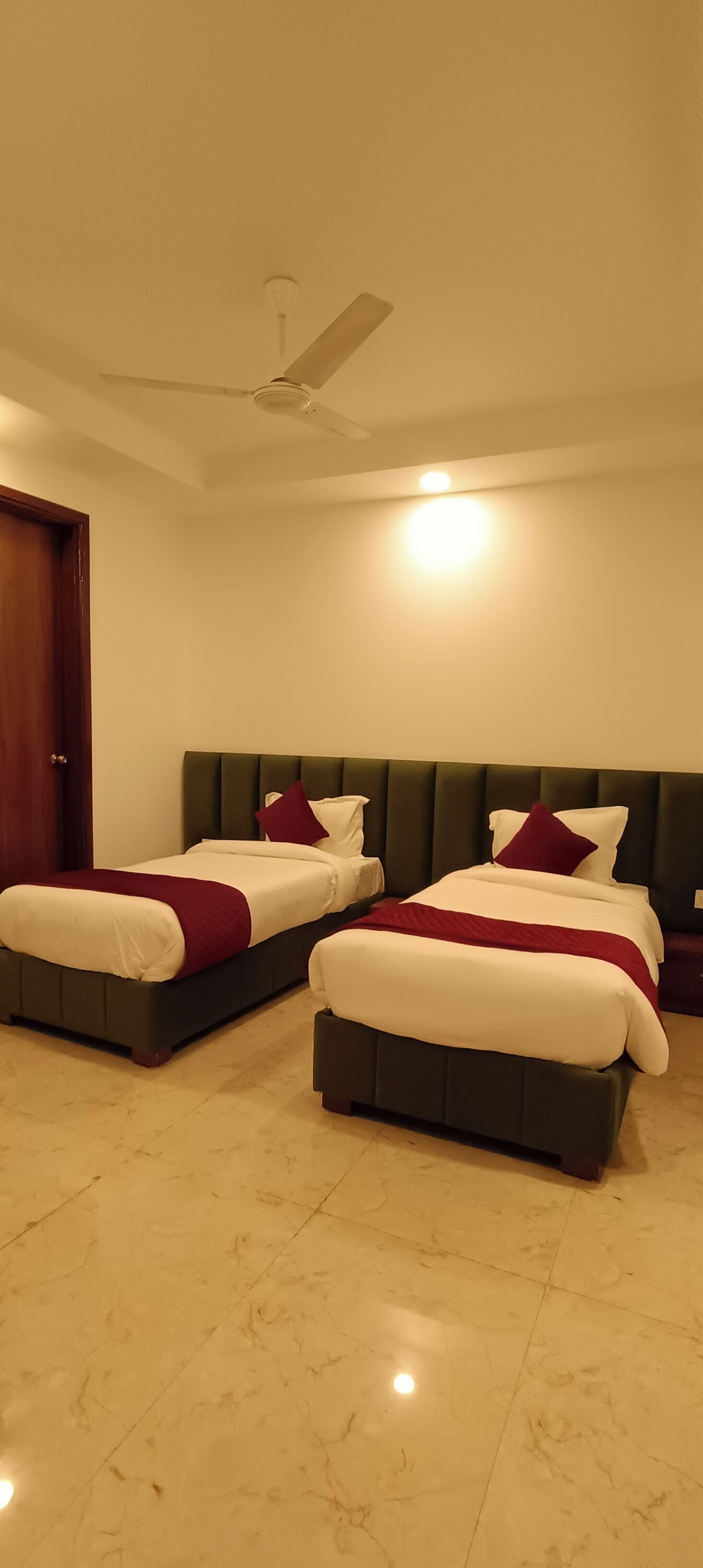 A hotel room with two beds, a ceiling fan, and a marble floor.