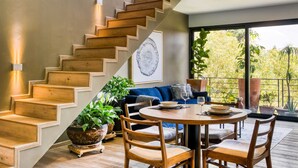 A modern interior with a wooden staircase, a round dining table, and a blue sofa. - Big PH Haven with rooftop, Condesa 2BR By Tasman (Ciudad de México)