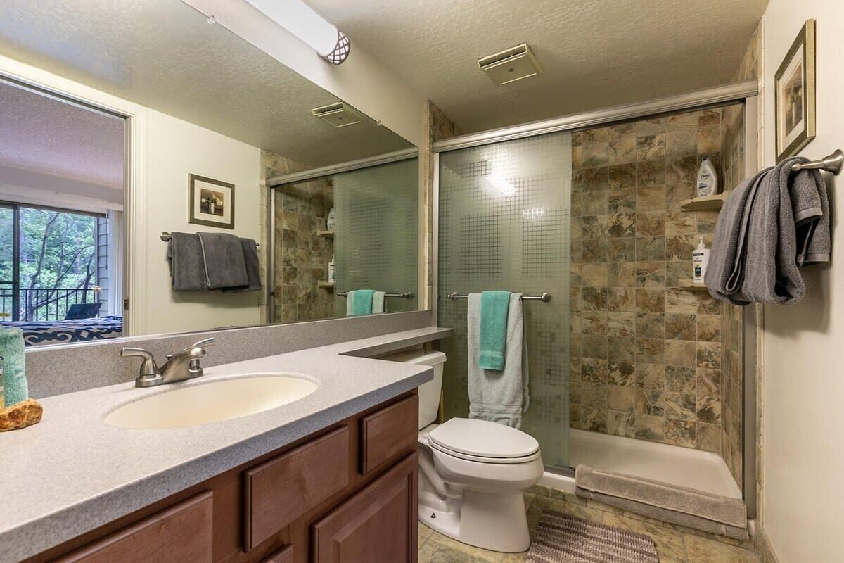 A bathroom with a double sink vanity, a toilet, a glass shower enclosure, and a bathtub.
