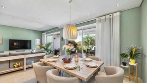 A modern dining area with a wooden table set for four, surrounded by textured chairs. - Luxury Villa in Serene Location w/ Pool & Private Garden (Quarteira)