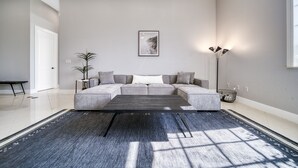 A modern living room with a grey sofa, a black coffee table, and a framed picture on the wall.