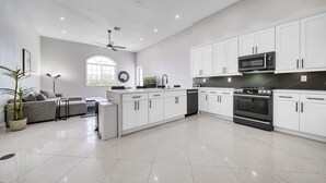 A modern kitchen with white cabinets, a built-in oven, and a microwave.