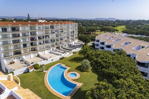Un hotel de varios pisos con piscina, mobiliario exterior y vistas al paisaje circundante.