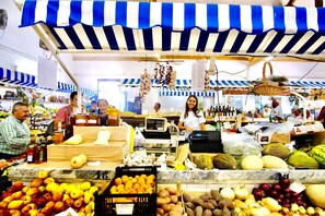 Un puesto de mercado con diversas frutas y verduras, incluyendo manzanas, naranjas y melones.