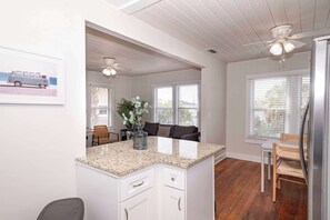 A kitchen with white cabinets, a granite countertop, and a ceiling fan.