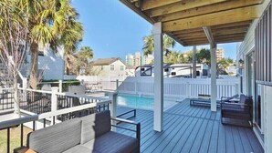 A covered deck with a pool, outdoor seating, and a view of a residential area. - Beach Retreat Complex w/Pool - Sleeps 25! (Jacksonville Beach)