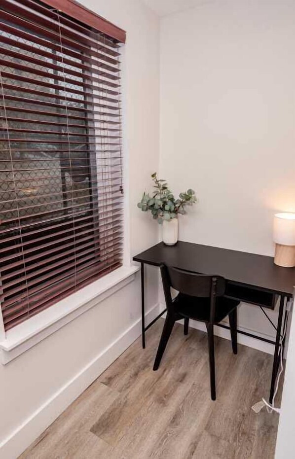 A corner room with a wooden desk, a chair, a potted plant, and a lamp.